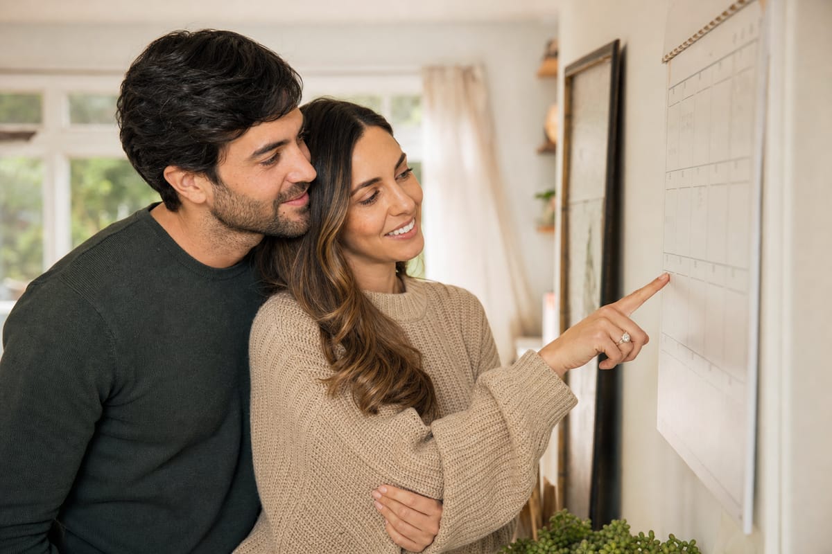A relaxed engaged couple looking at a calendar together